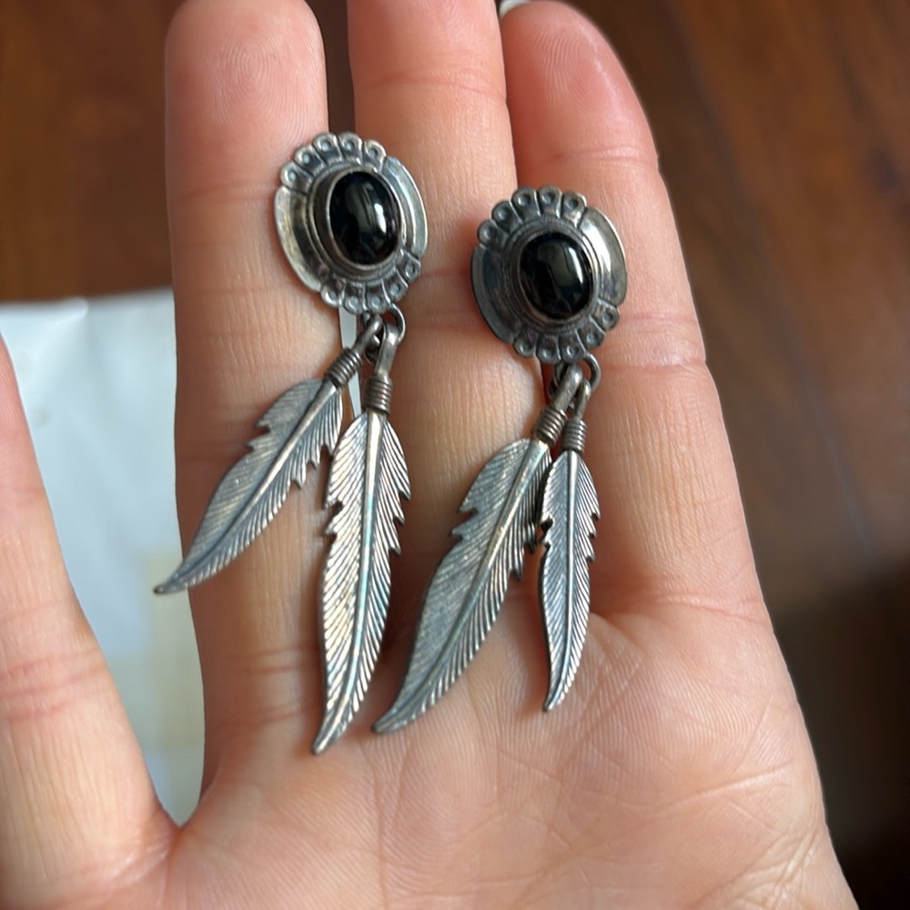 Silver earrings with dangly silver feathers.
